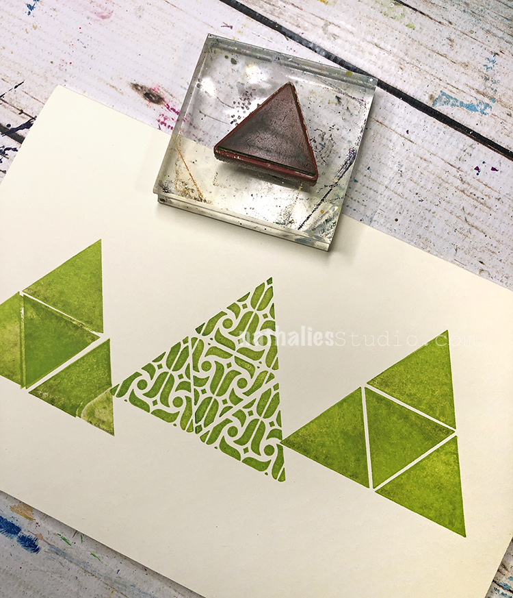 three hand stamped triangle shapes in a row with a triangle rubber stamp 